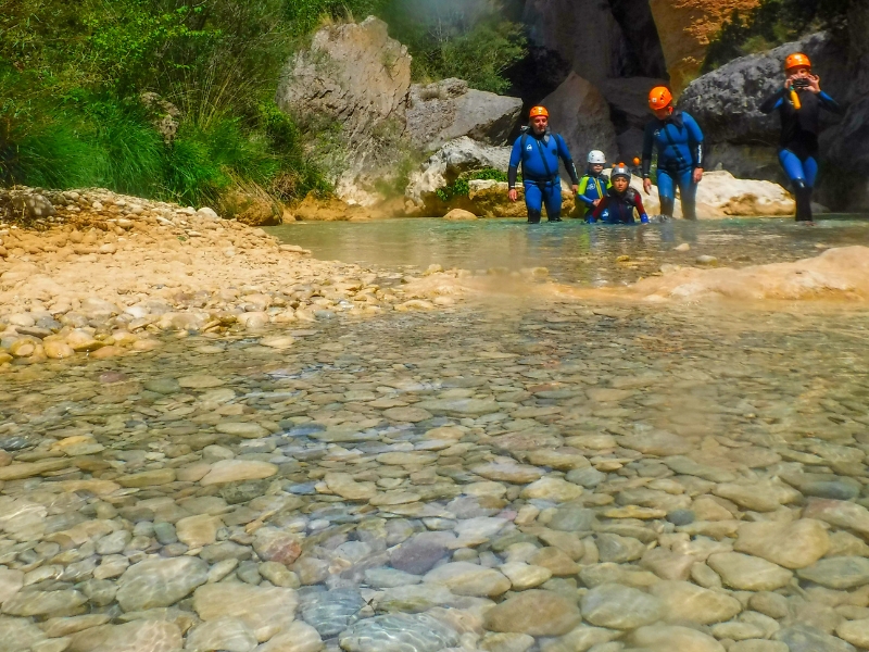 Barranquistas caminando por la parte final del Barranco Peonera en una zona de poca profundidad con pequeñas rocas lisas