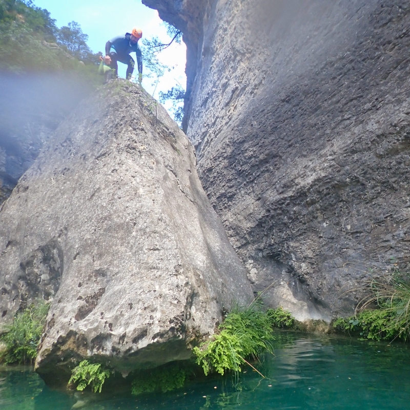 Persona subida a lo alto de una roca rodeada de agua en un barranco de Alquézar