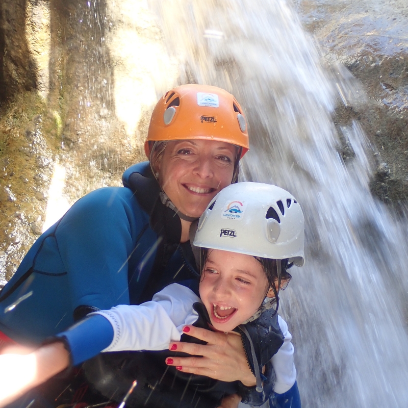 Madre con su hija junto a una cascada practicando barranquismo familiar