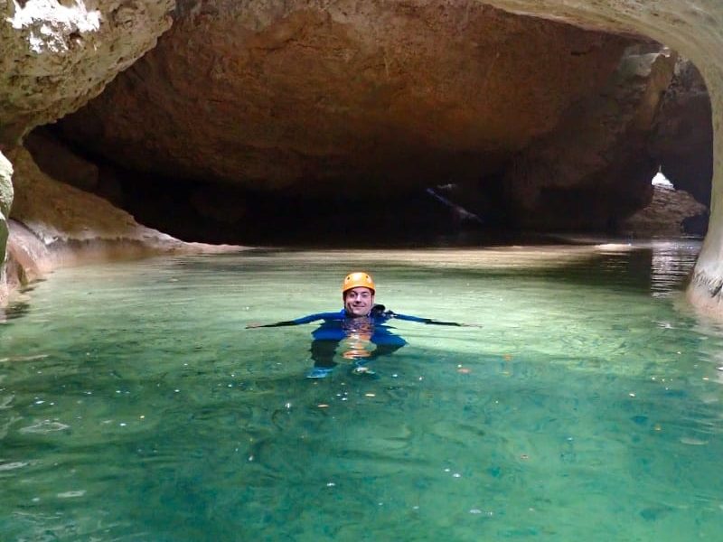 Persona en el interior de una cavidad de agua turquesa practicando barranquismo en Alquézar
