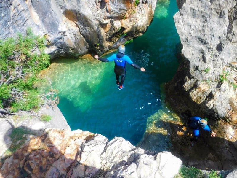 persona saltando al agua turquesa en la actividad de barranquismo en Sierra de Guara