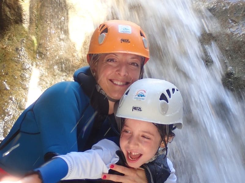 Madre con su hija junto a una cascada practicando barranquismo familiar